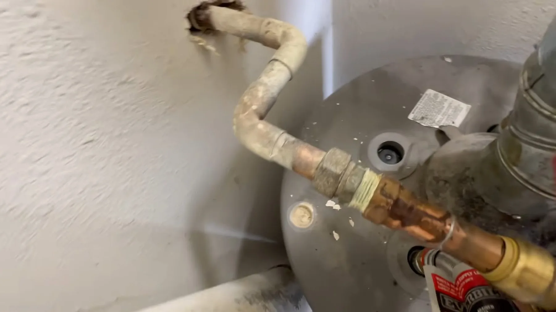 Wrench positioned over a water heater to remove the anode rod