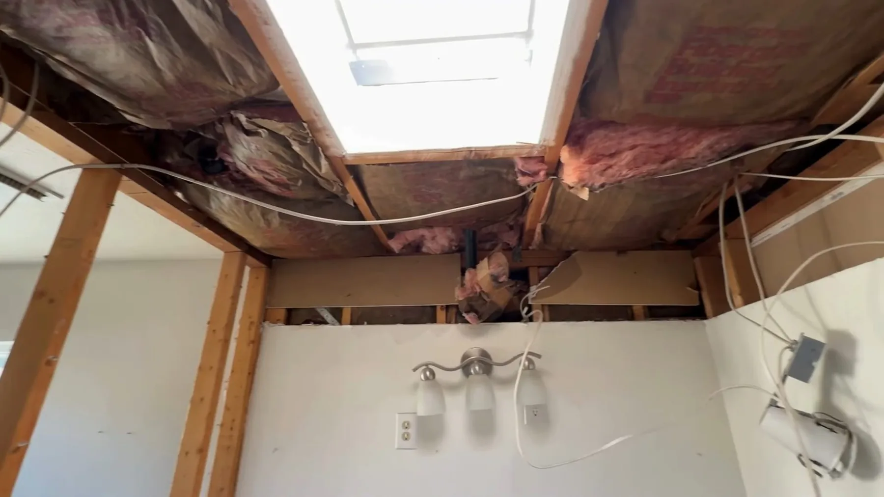 Bathroom ceiling with exposed joists during an active repair
