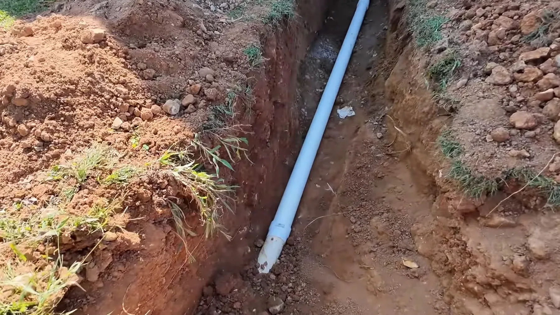 Replacement septic pipe laid in a trench ahead of backfilling