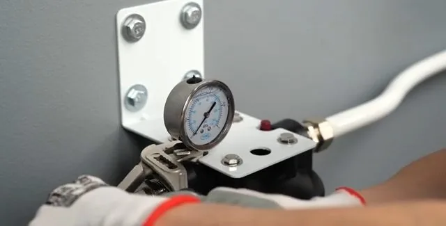Pressure gauge on a filtration bracket being checked during service