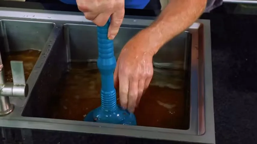Clogged kitchen drain viewed through the sink strainer before cleaning