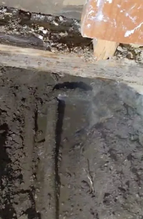 Close-up of a concrete slab opening cut to access a leaking line underneath