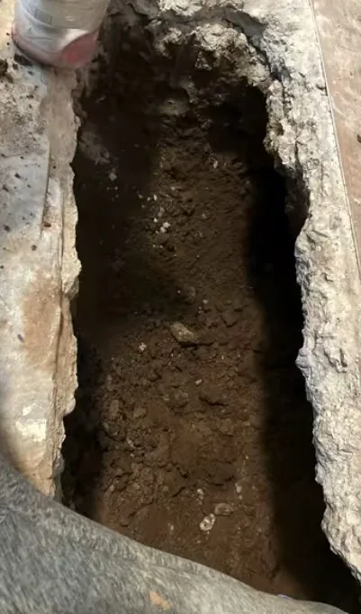 Concrete slab trench cut open beside an exposed pipe