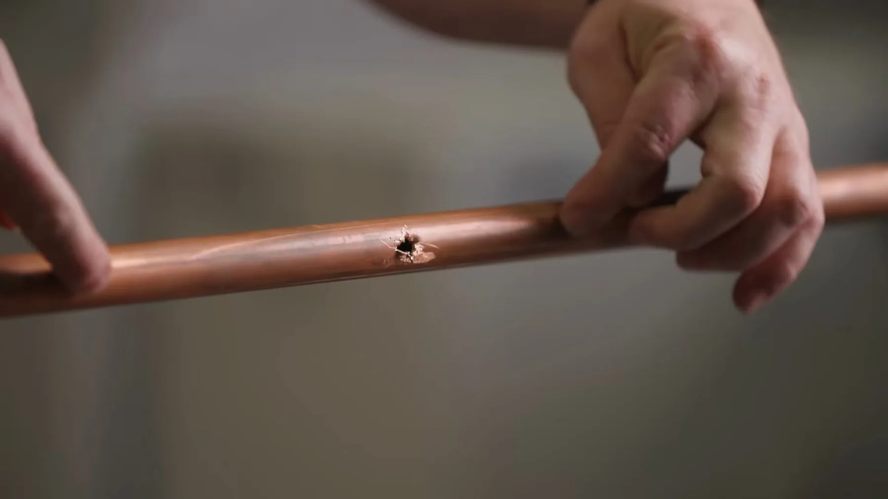 Section of repaired copper pipe held up for inspection