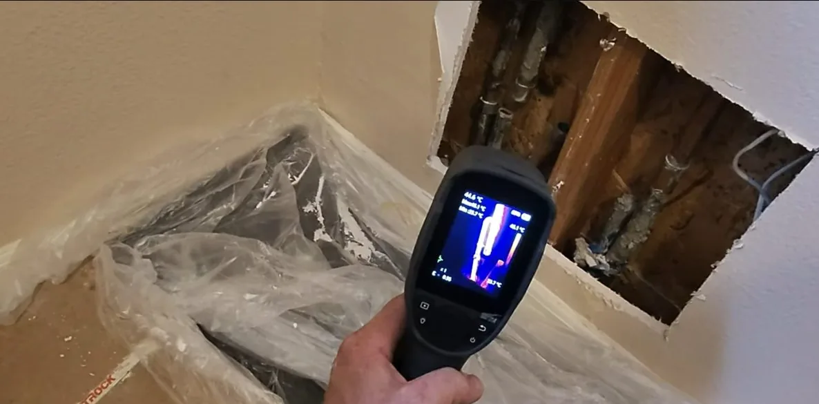 Digital leak detector screen held over a floor slab during a Cave Creek leak search