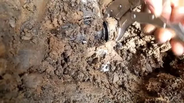 Broken water line exposed beneath standing muddy water