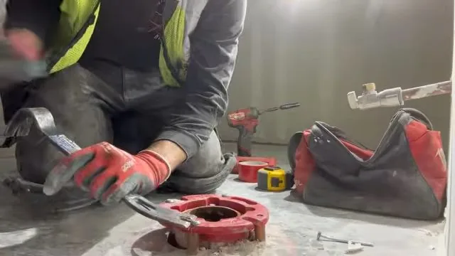 Commercial toilet flange being ground down at floor level for a proper fit