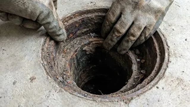 Wrench loosening a sink P-trap to check for a local blockage