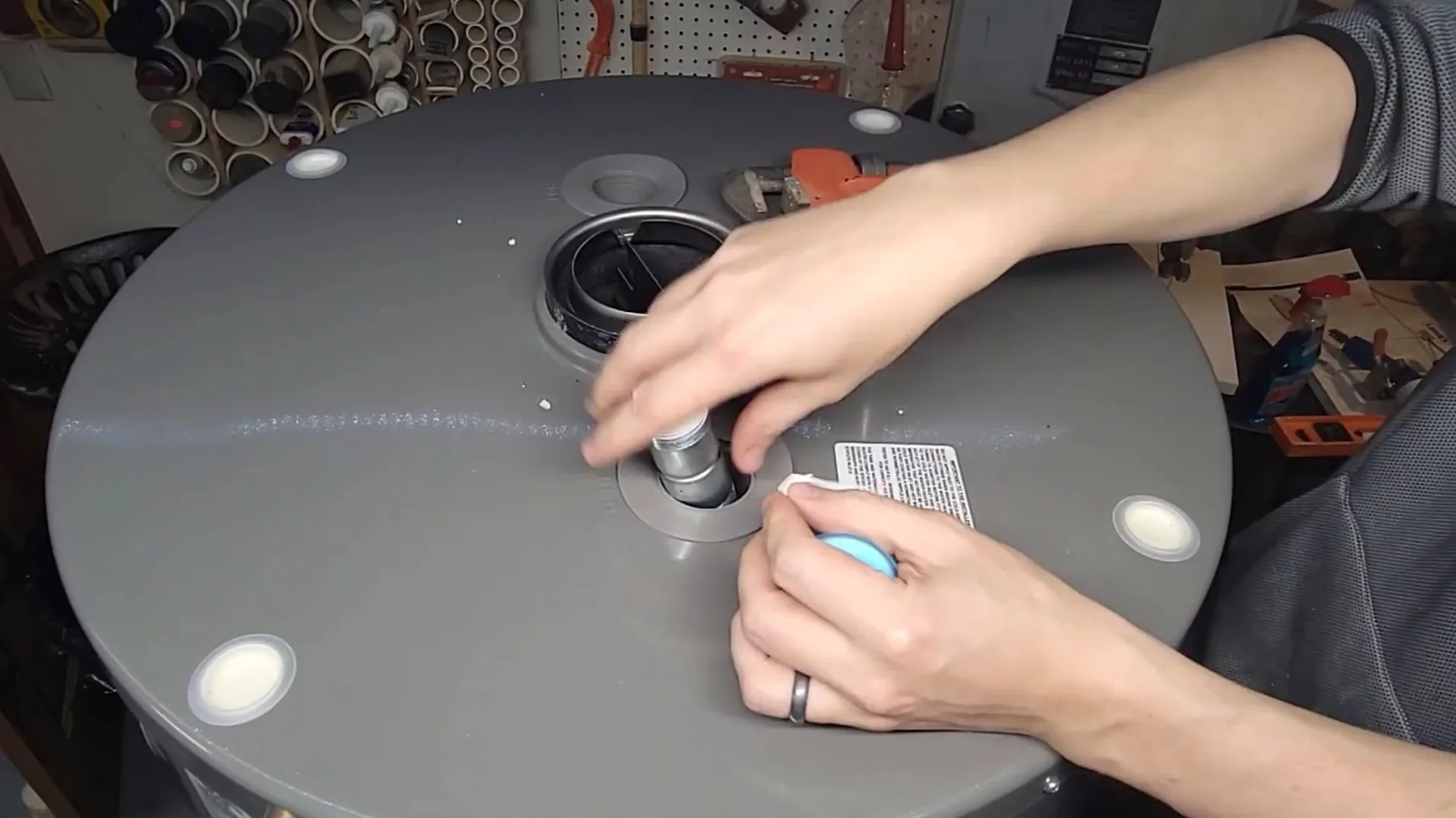 Plumber tightening a fitting at the top of a water heater