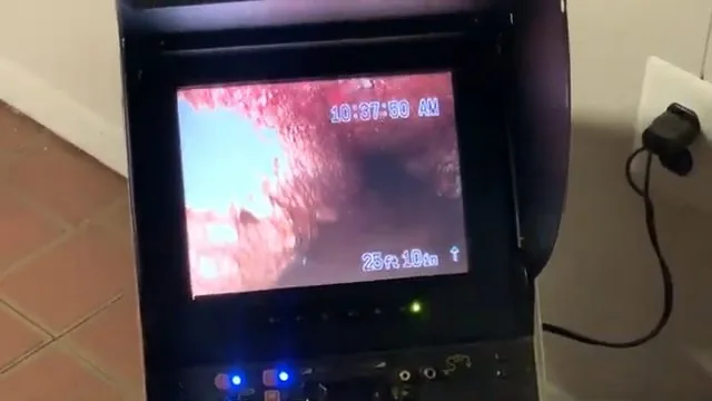 Technician pointing out a blockage visible on a sewer camera monitor