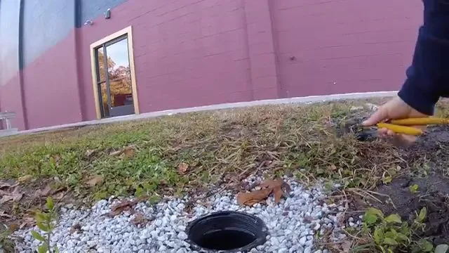 Camera cable being positioned at a sewer line access point before inspection