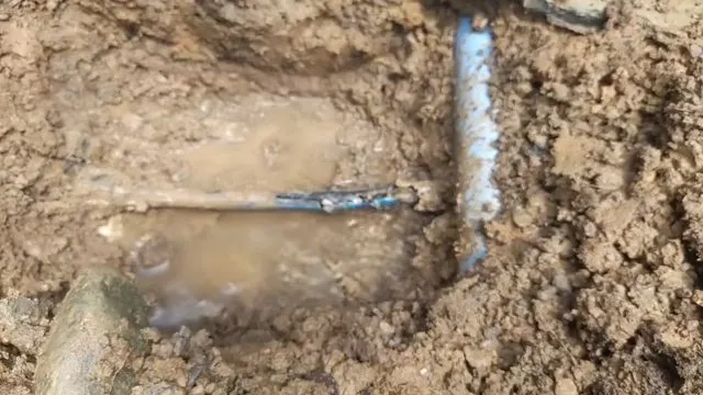 Technician searching for a leak source inside a partially flooded excavation