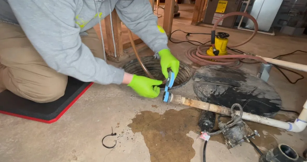 Worker replacing a sump pump inside its basin